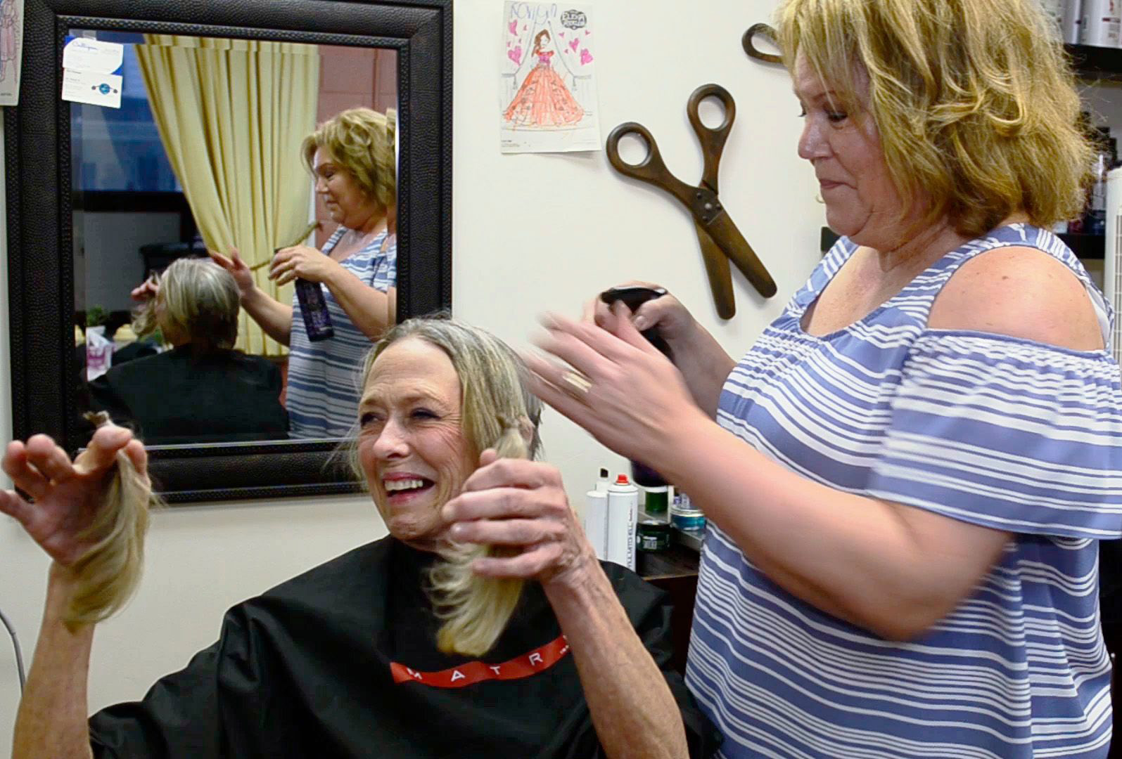 Patti Tucker holds up locks of her hair cut by her friend Sandy Lagrou, manager of Friends Salon & Spa. Tucker will donate the hair to be used to make a child's wig. 
