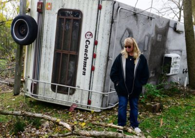 Connie Weyer stands in front of her 32-foot Coachman camper. The force of the tornado picked the camper up, lifted it over a 10-foot deck and overturned it on its side.