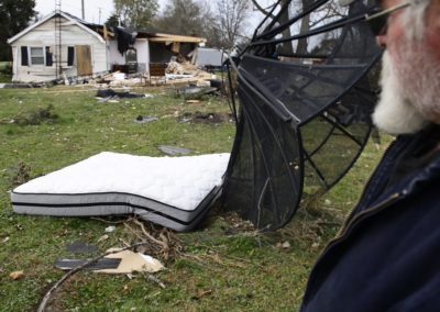 Kevin Weyer looks at his mother-in-law's mattress blown halfway across the yard by an EF 1 tornado. His mother-in-law was in the living room when the tornado hit. She described the tornado as sounding like a whistle which only lasted a few seconds. The force of the wind blew her bedroom door shut. The door then blew open, and when she looked out the bedroom was gone.